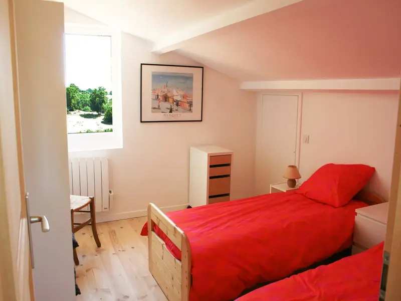 Chambre mansardée avec deux lits simples aux couvre-lits rouges