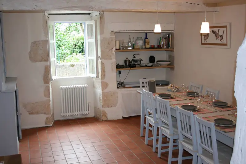 Table dressée pour dix personnes, murs en pierre et fenêtre sur le jardin