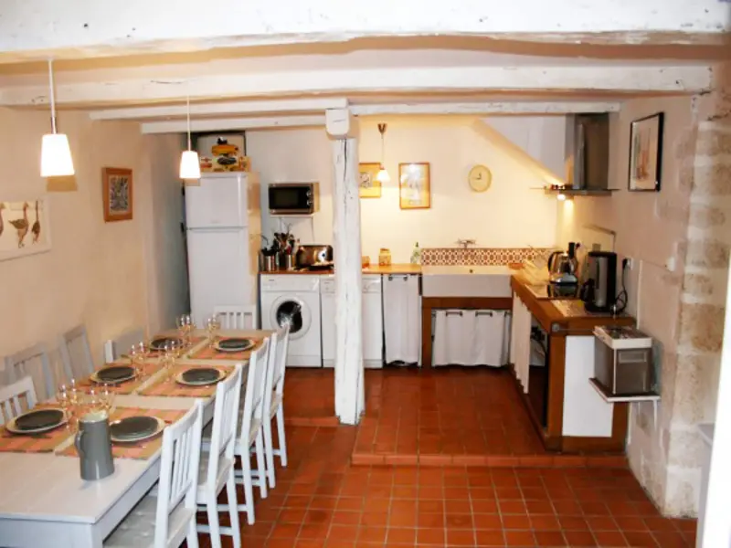 Grande cuisine équipée avec tomettes, poutres et table pour dix