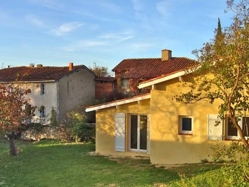 La dépendance aux murs ocre au premier plan, la maison principale derrière