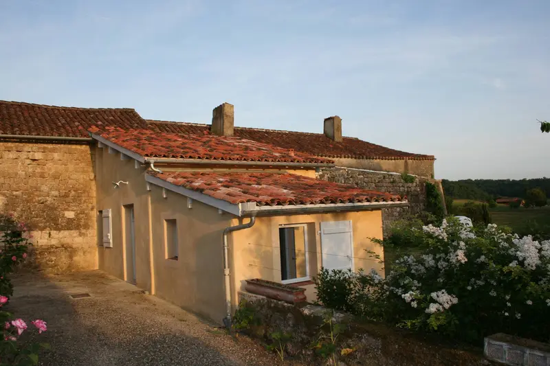 Dépendance aux tuiles canal dans la lumière du soir, rosiers en fleurs