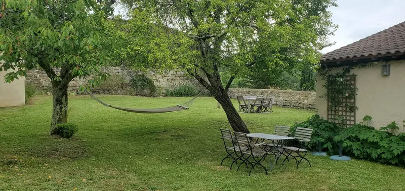 Pelouse ombragée avec hamac, table de jardin et dépendance