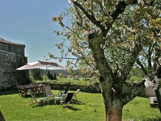Salon de jardin sous un parasol au pied du rempart