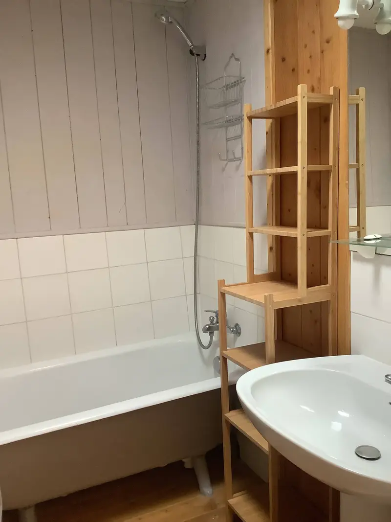Salle de bain avec baignoire, vasque et étagère en bois