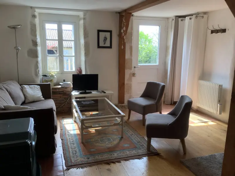 Coin salon avec canapé, fauteuils, table basse et télévision